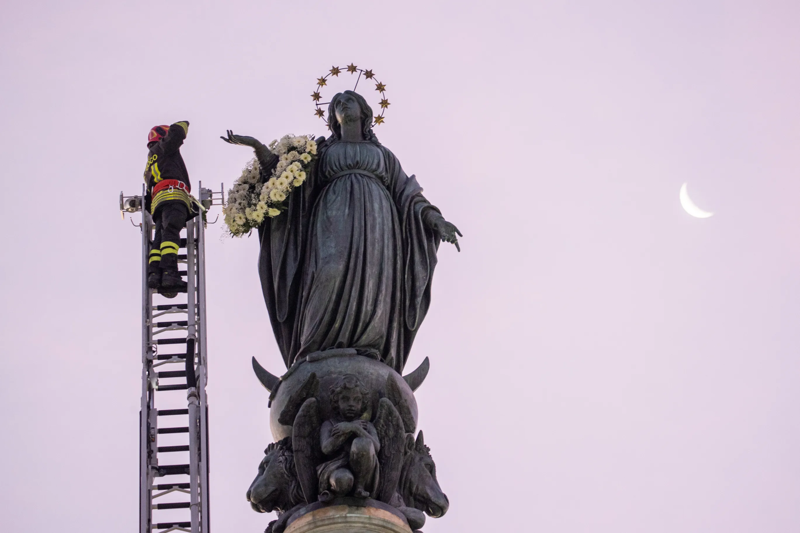 A firefighter in Rome pays tribute to the Blessed Virgin Mary by laying a wreath of fresh flowers at her statue atop a column near the Spanish Steps at dawn on Dec. 8, 2023. Pope Francis will preside at a ceremony at the statue in the afternoon to celebrate the solemnity of the Immaculate Conception. Credit: Daniel Ibanez/CNA