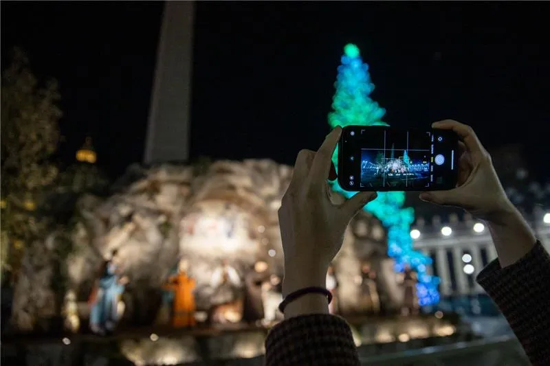 A spectator takes a photo of the Nativity scene and Christmas tree unveiled in St. Peter's Square at the Vatican on Dec. 9, 2023. Credit: Daniel Ibañez/EWTN