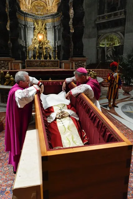Before the wooden coffin is closed, Benedict XVI’s personal secretary Archbishop Georg Gänswein and Monsignor Diego Giovanni Ravelli, the Vatican’s lead master of ceremonies for papal liturgies, place a white veil over the late pope’s face. The action on Jan. 4, 2023, is part of the funeral rites for popes. Vatican Media