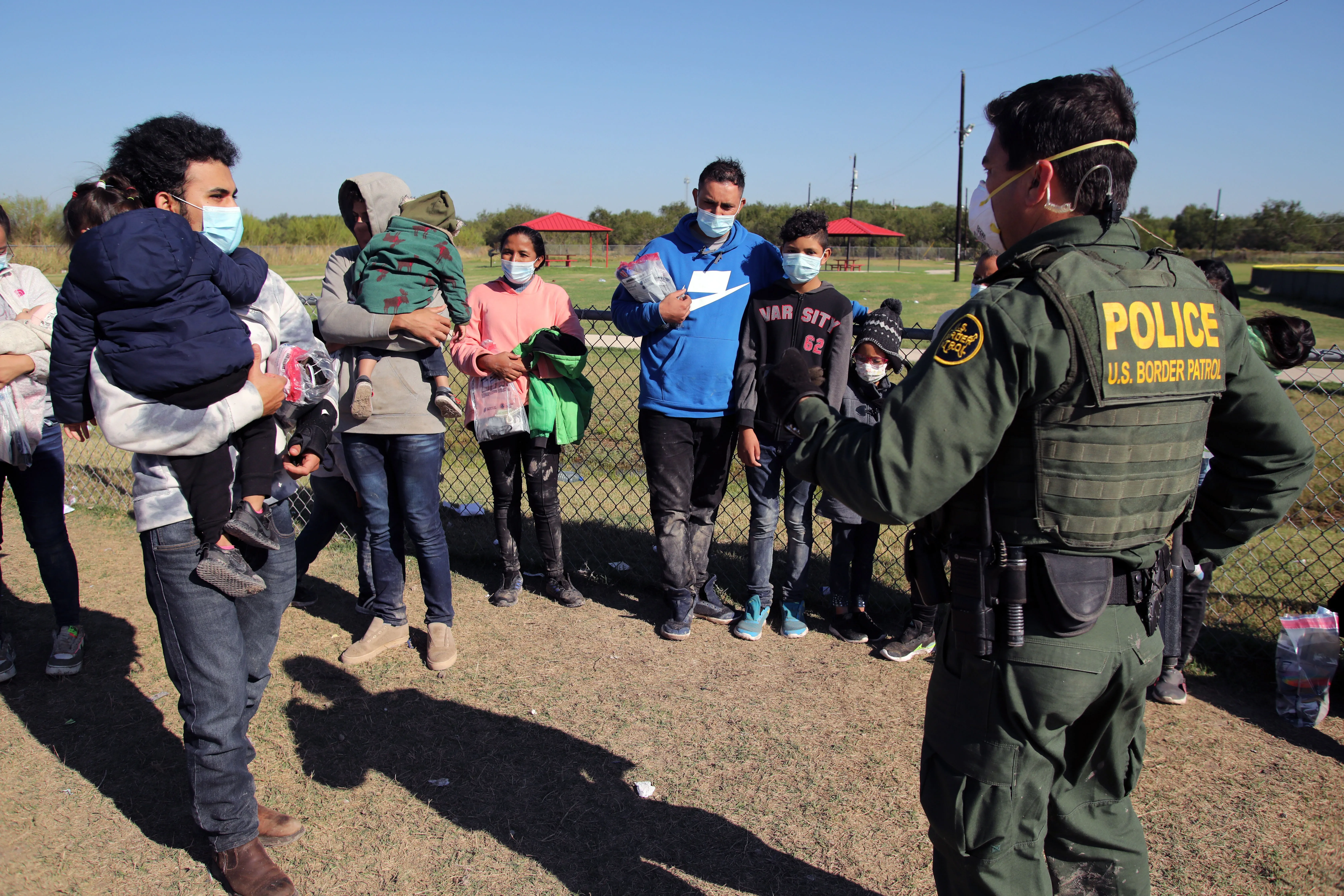 A male Border Patrol agent in La Joya, Texas, speaks in November 2021 with a Honduran man holding his daughter and waiting to be transported to a processing center after turning himself in to seek asylum.?w=200&h=150