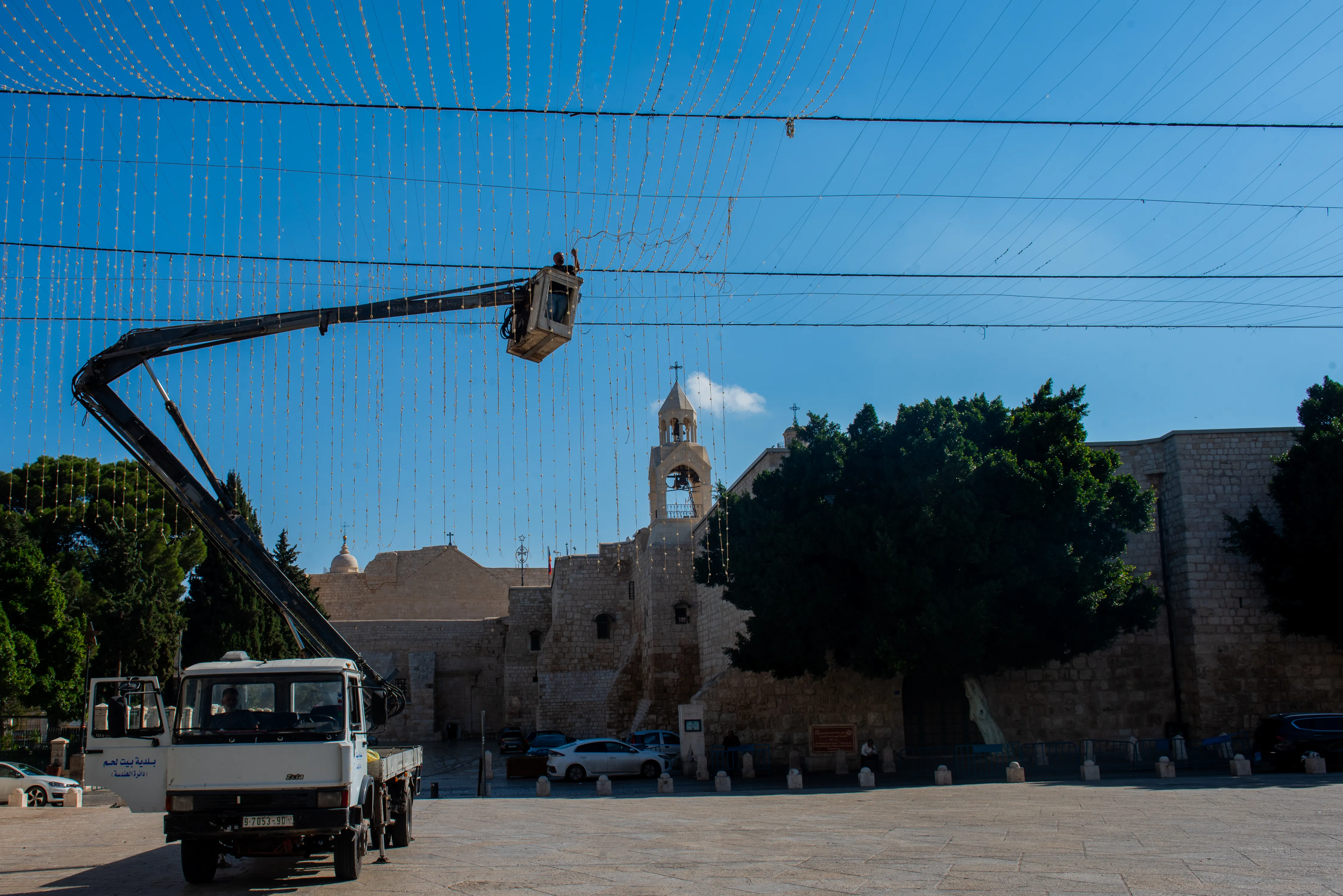 Following the municipality's decision to suspend Christmas events and remove decorations, workers are busy dismantling the light canopy on Manger Square in Bethlehem. Credit: Marinella Bandini