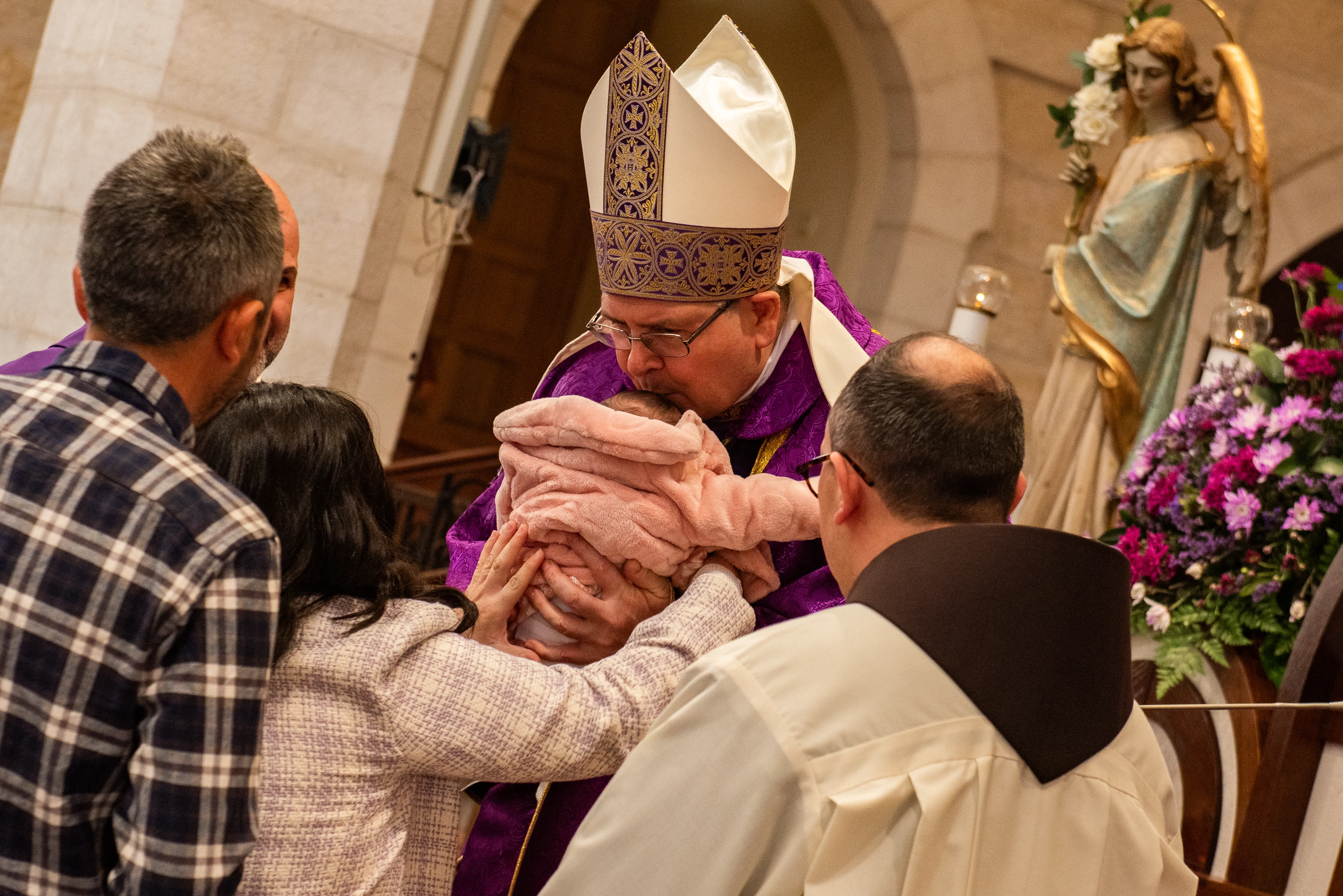 The custos of the Holy Land, Father Francis Patton, during the offertory of the solemn Mass of the first Sunday of Advent in Bethlehem receives a baby girl making her entrance into the Church for the first time, approximately 40 days after her birth, a tradition still observed in this land. Dec. 3, 2023. Credit: Marinella Bandini