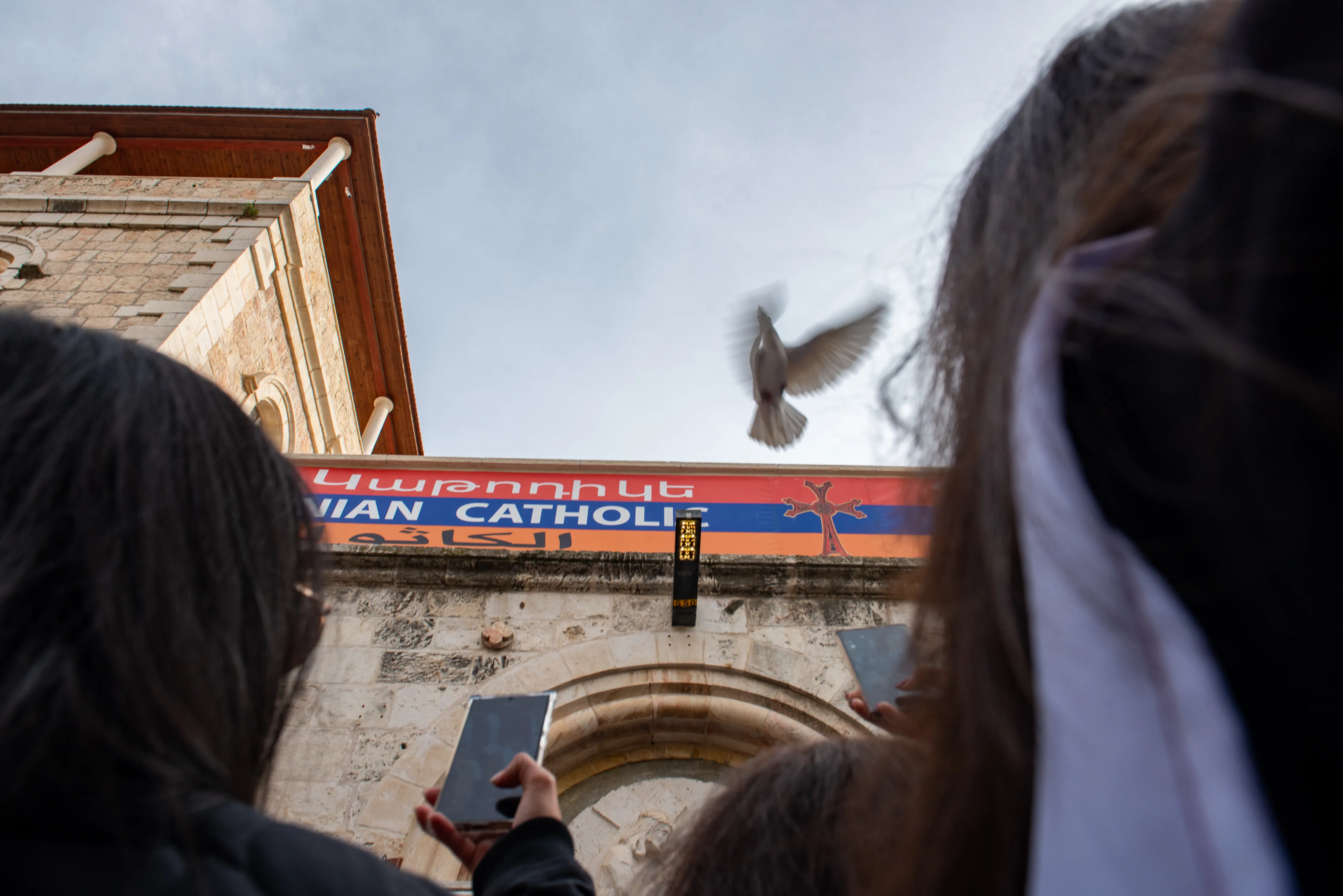 A dove takes flight immediately after being released in front of the fourth station of the Way of the Cross, along the Via Dolorosa in Jerusalem, during the Way of the Cross for Christian school students in Jerusalem, held on Friday, Feb. 23, 2024. At each station, two children released a pair of doves, a visible sign of the prayer for peace. Credit: Marinella Bandini