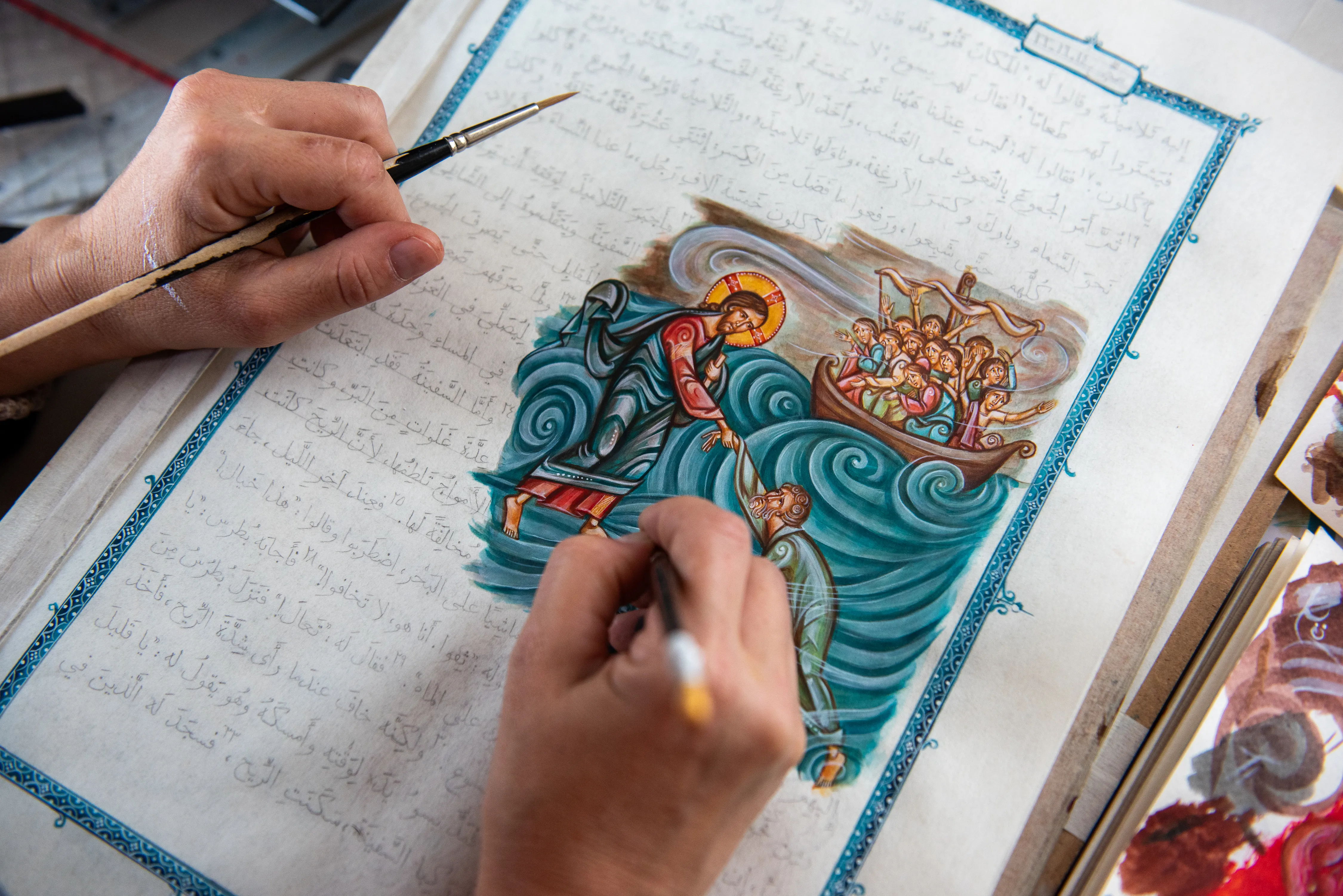 Iconographer María Ruiz Rodríguez at work in her studio. The image depicts Jesus walking on water and taking St. Peter's sinking hand (Mt 14:22-33). Credit: Marinella Bandini