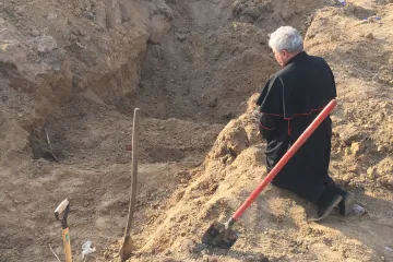 Papal envoy Cardinal Konrad Krajewski prays at a mass grave in Ukraine on Good Friday, April 15, 2022.