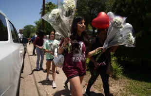 People arrive to drop off flowers at a makeshift memorial outside the Robb Elementary School on May 26, 2022 in Uvalde, Texas. - Grief at the massacre of 19 children at the elementary school in Texas spilled into confrontation on May 25, as angry questions mounted over gun control -- and whether this latest tragedy could have been prevented. The tight-knit Latino community of Uvalde on May 24 became the site of the worst school shooting in a decade, committed by a disturbed 18-year-old armed with a legally bought assault rifle. Allison Dinner/AFP via Getty Images.