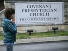 A woman prays at a makeshift memorial for victims outside the Covenant School building at the Covenant Presbyterian Church on March 28, 2023, following the March 27, 2023, shooting at the school in Nashville, Tennessee.