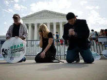 (left to right) Rev. Pat Mahoney, Peggy Nienaber of Faith and Liberty, and Mark Lee Dickson of Right to Life East Texas pray in front of the U.S. Supreme Court on April 21, 2023, in Washington, D.C. Organized by The Stanton Public Policy Center/Purple Sash Revolution, the small group of demonstrators called on the Supreme Court to affirm Federal District Court Judge Matthew Kacsmaryk’s ruling that suspends the Food and Drug Administration’s approval of the abortion pill mifepristone.