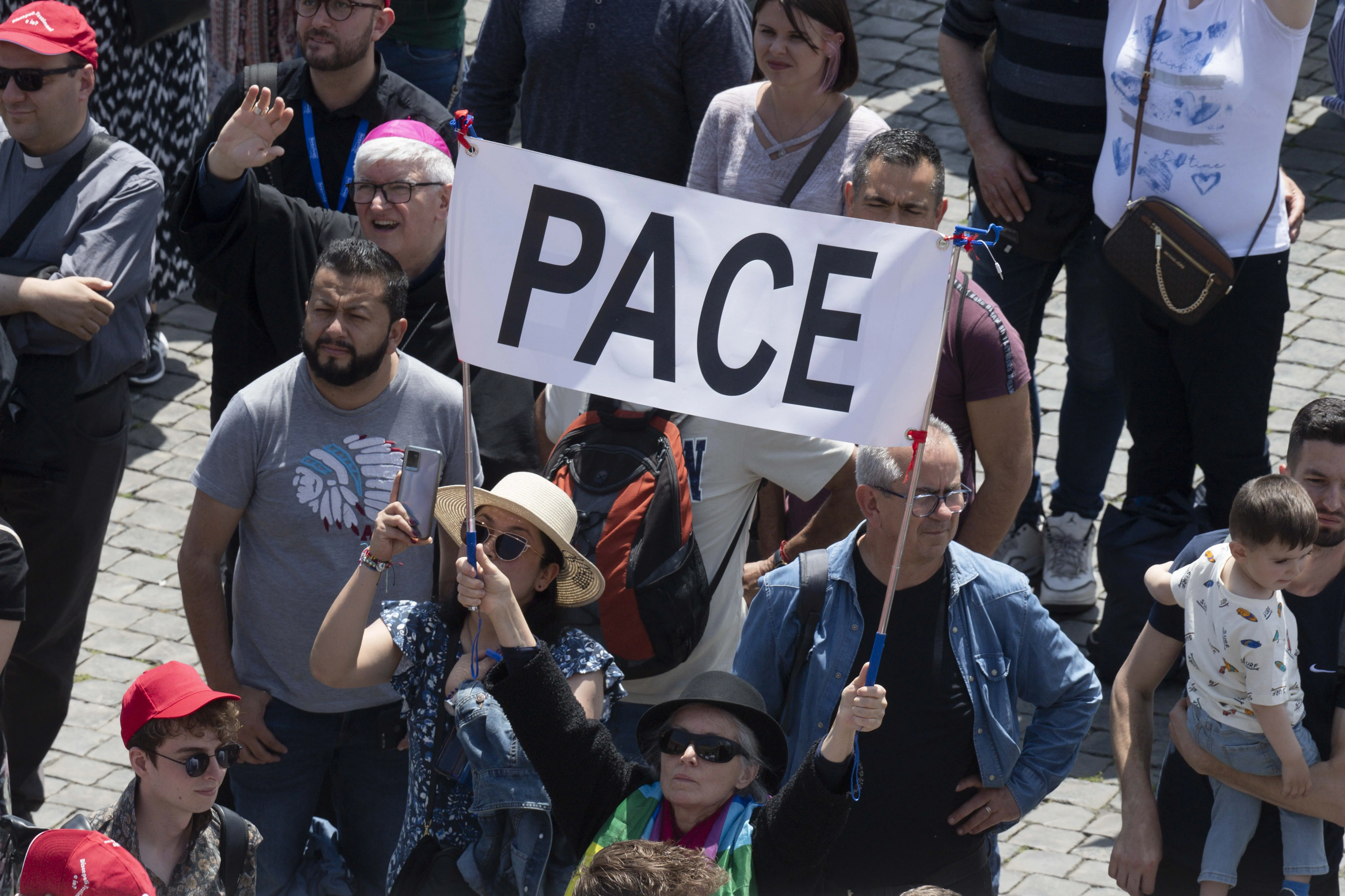 Pilgrims in St. Peter's Square hold up a sign that says "pace," which means "peace" in Italian. Vatican Media