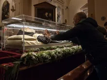 A man places his hands on the glass urn holding the remains of St. Pio in Pietrelcina, Italy, in 2016. St. Pio was found to be in a state of partial deterioration and partial preservation when his coffin was opened in 2008, but experts present at the exhumation have said there was no supernatural quality to what was preserved. Artificial preservation techniques have since been applied to conserve his body from further deterioration and a lifelike mask has been placed over his skull.