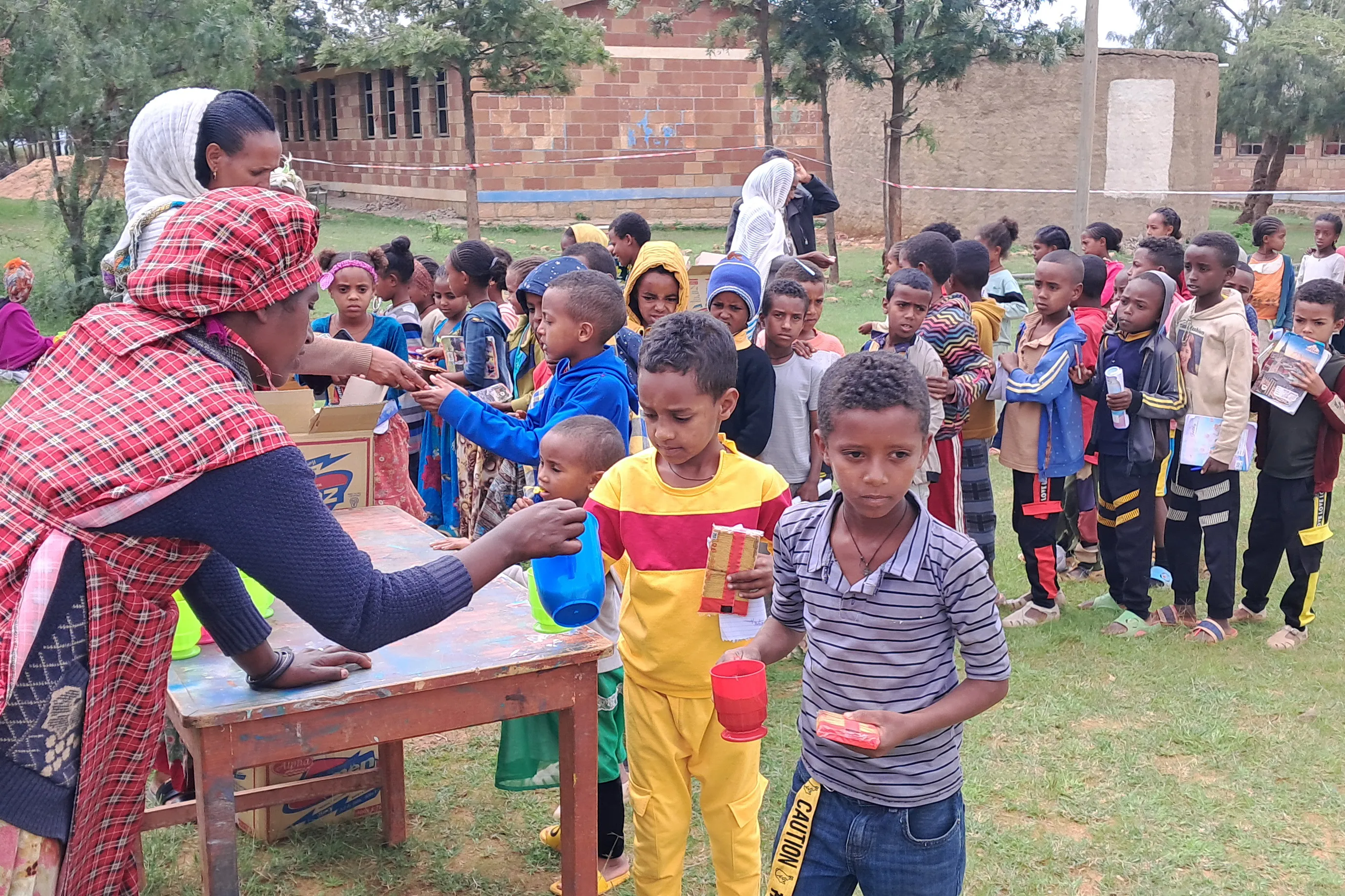 Schoolchildren in Tigray, Ethiopia, eat biscuits and tea provided by Mary's Meals. Copyright Mary's Meals