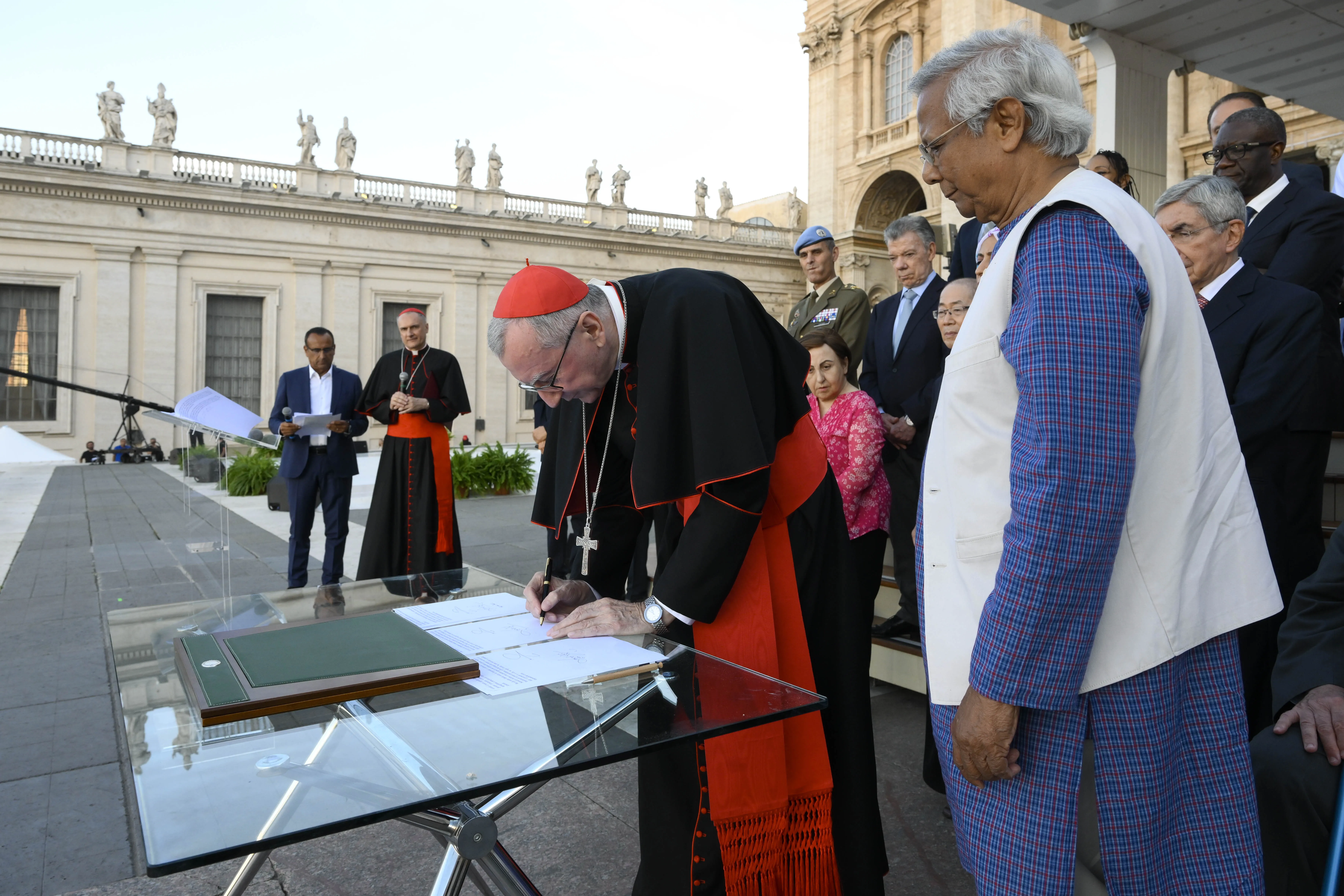 Cardinal Pietro Parolin signs a declaration on human fraternity on behalf of Pope Francis while Muhammad Yunus, winner of the Nobel Peace Prize in 2006, and other Nobel laureates, look on, during the #NotAlone human fraternity event in St. Peter's Square June 10, 2023. Vatican Media.