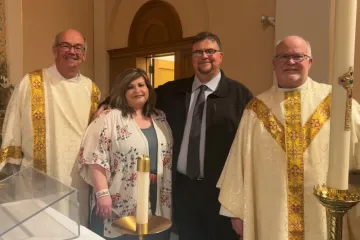Recent convert Steve Dow and his wife, Amanda, pose for a photo with Deacon M.J. Kersenbrock, left, and Father Bernard Starman after the Easter Vigil April 16, 2022 at St. Patrick Church in O’Neill, Nebraska.
