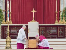 Archbishop Georg Gänswein (right), the longtime personal secretary for Benedict XVI,  kneels to kiss the book of the Gospels atop the coffin of the pope emeritus on Jan. 5, 2023, in St. Peter's Square